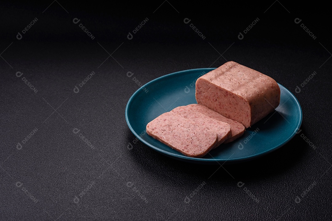 Delicioso presunto rosa enlatado com sal, especiarias e ervas sobre um fundo escuro de concreto