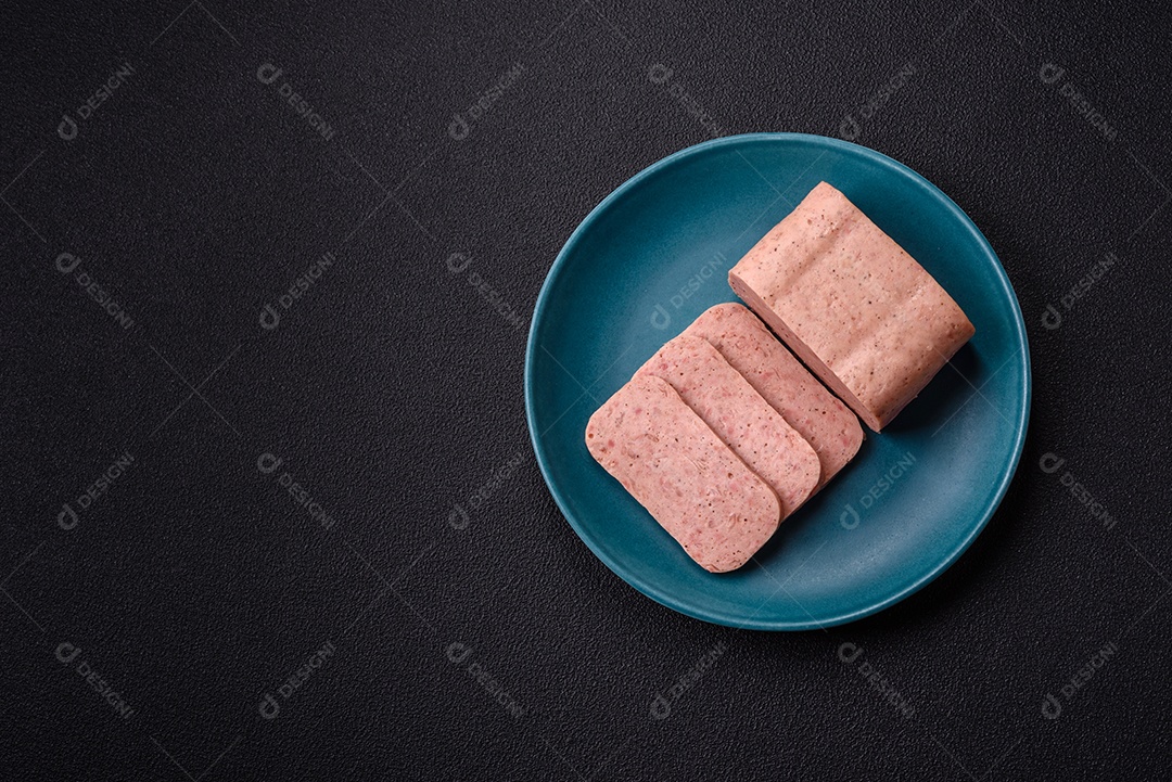 Delicioso presunto rosa enlatado com sal, especiarias e ervas sobre um fundo escuro de concreto