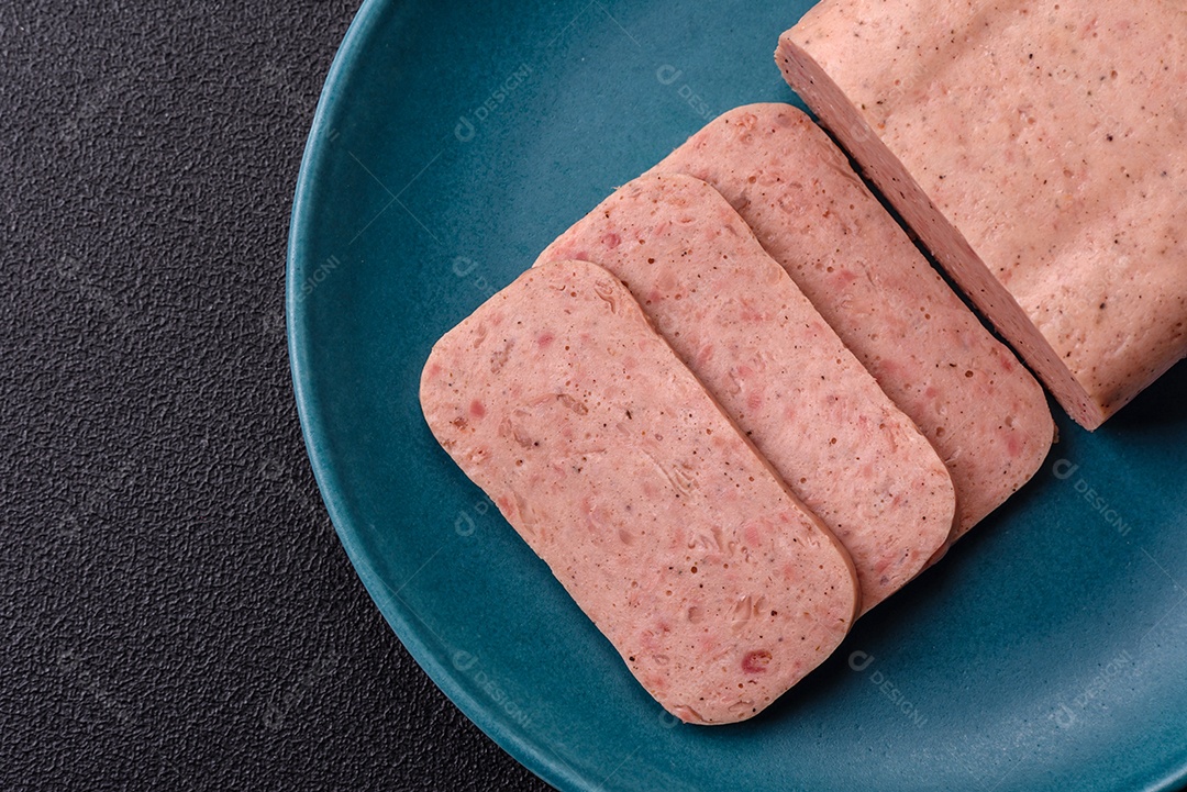 Delicioso presunto rosa enlatado com sal, especiarias e ervas sobre um fundo escuro de concreto