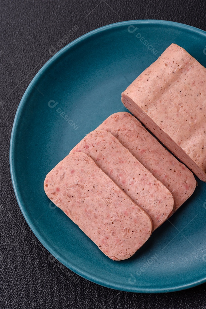 Delicioso presunto rosa enlatado com sal, especiarias e ervas sobre um fundo escuro de concreto