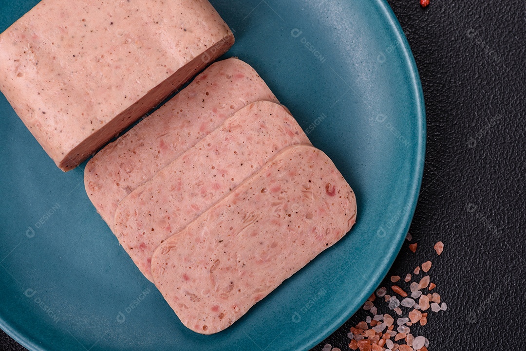Delicioso presunto rosa enlatado com sal, especiarias e ervas sobre um fundo escuro de concreto