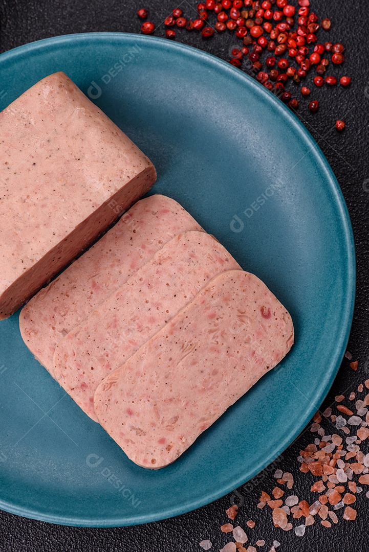 Delicioso presunto rosa enlatado com sal, especiarias e ervas sobre um fundo escuro de concreto