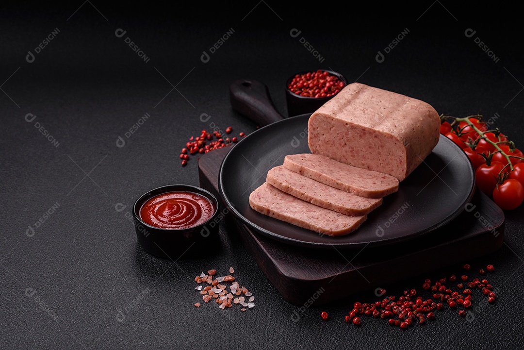 Delicioso presunto rosa enlatado com sal, especiarias e ervas sobre um fundo escuro de concreto