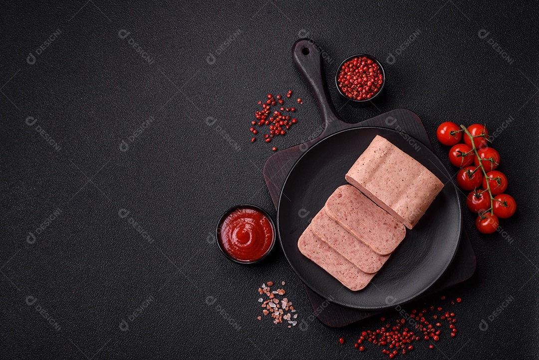 Delicioso presunto rosa enlatado com sal, especiarias e ervas sobre um fundo escuro de concreto