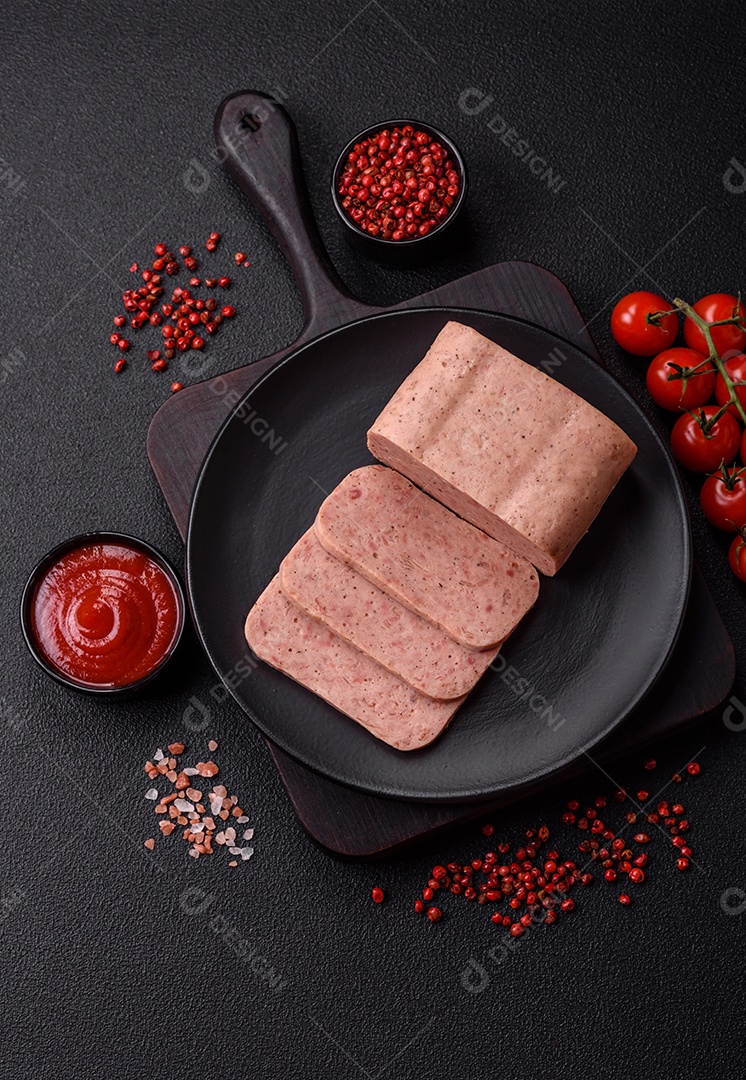 Delicioso presunto rosa enlatado com sal, especiarias e ervas sobre um fundo escuro de concreto