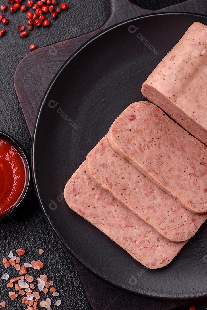 Delicioso presunto rosa enlatado com sal, especiarias e ervas sobre um fundo escuro de concreto