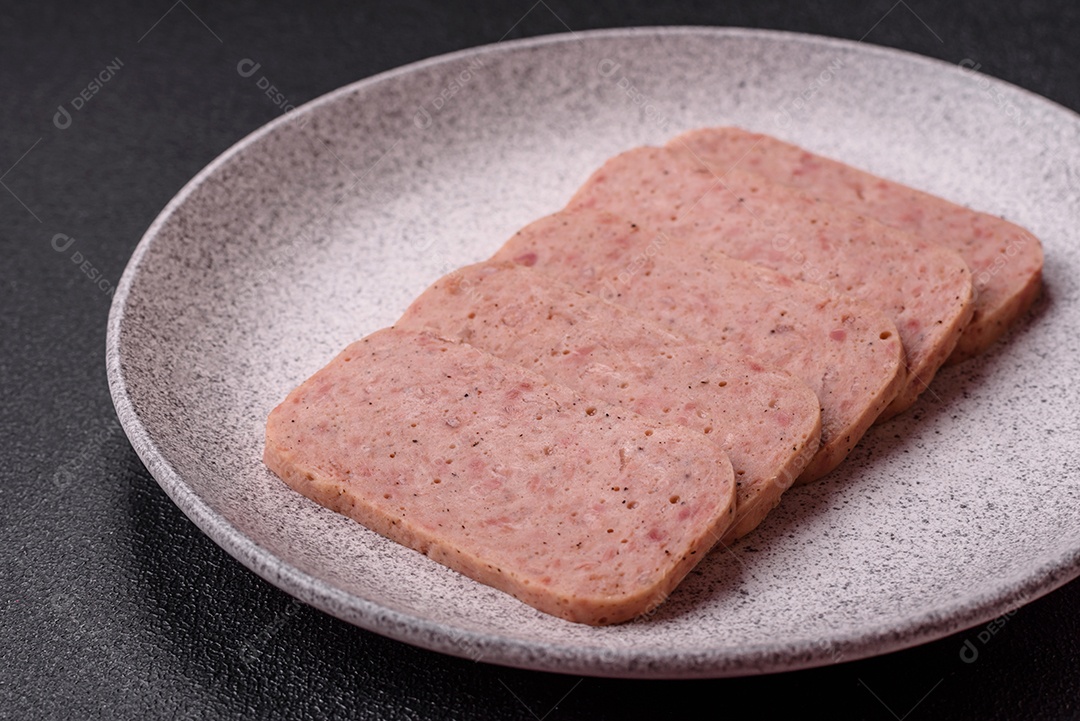 Delicioso presunto rosa enlatado com sal, especiarias e ervas sobre um fundo escuro de concreto