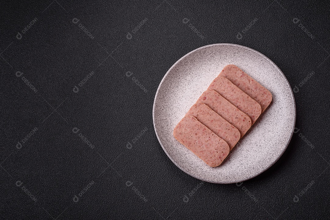 Delicioso presunto rosa enlatado com sal, especiarias e ervas sobre um fundo escuro de concreto