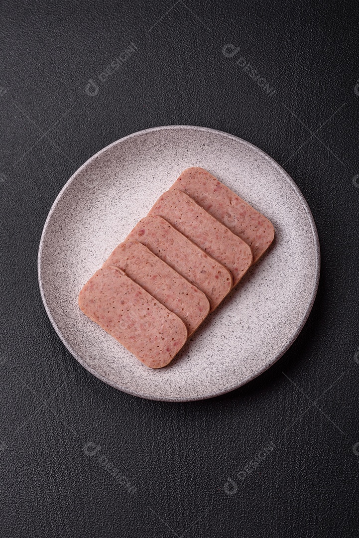 Delicioso presunto rosa enlatado com sal, especiarias e ervas sobre um fundo escuro de concreto