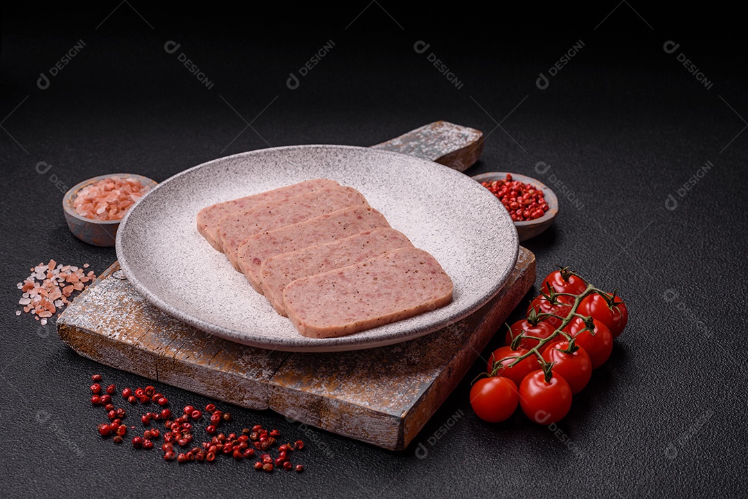 Delicioso presunto rosa enlatado com sal, especiarias e ervas sobre um fundo escuro de concreto