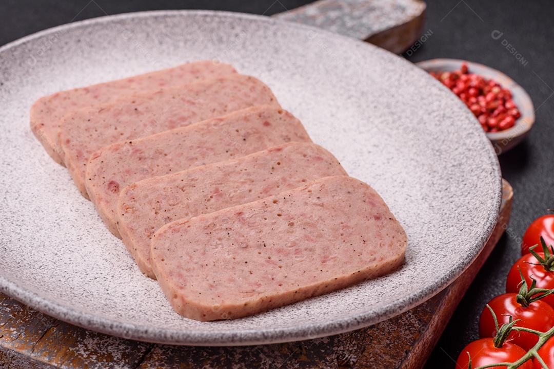 Delicioso presunto rosa enlatado com sal, especiarias e ervas sobre um fundo escuro de concreto