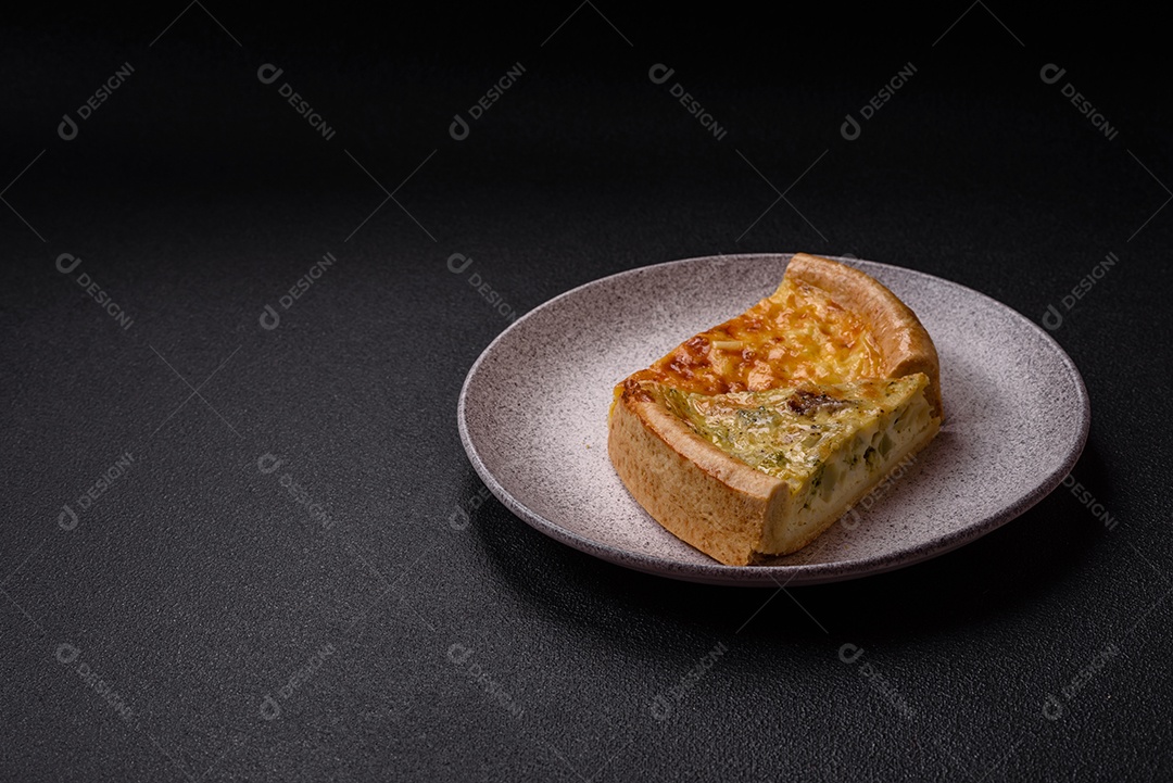 Deliciosa quiche com brócolis, frango ou salmão e queijo com sal e especiarias sobre fundo escuro de concreto