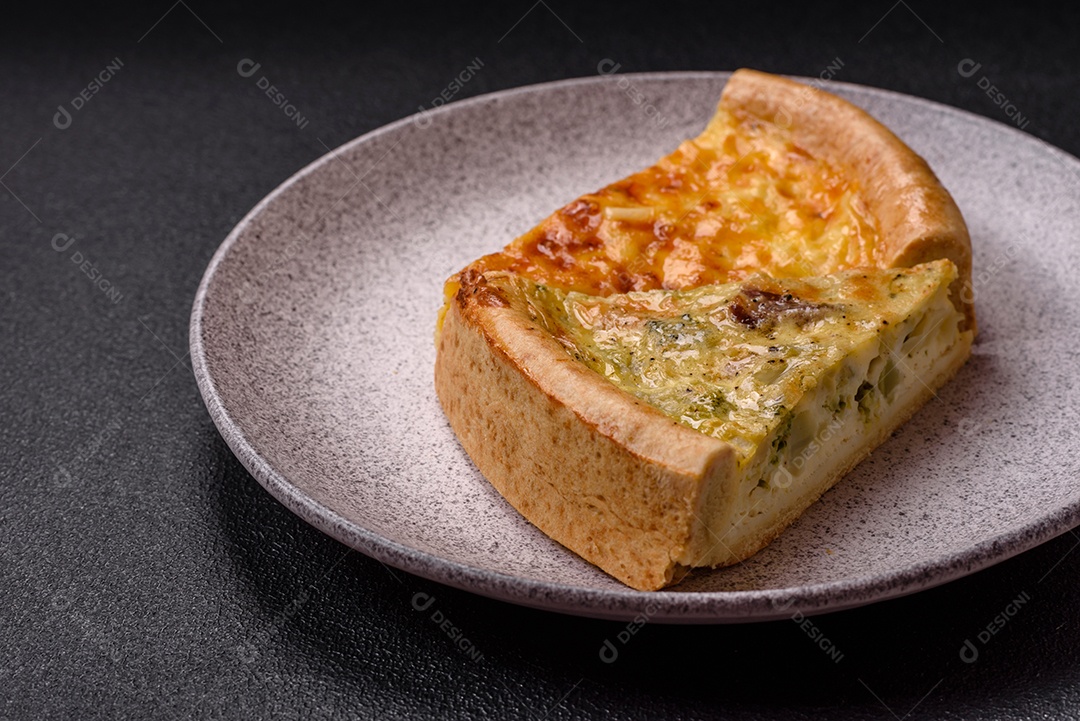 Deliciosa quiche com brócolis, frango ou salmão e queijo com sal e especiarias sobre fundo escuro de concreto