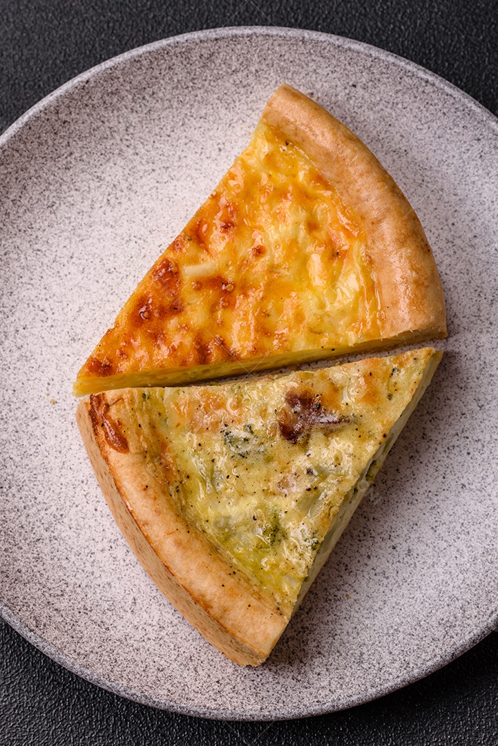 Deliciosa quiche com brócolis, frango ou salmão e queijo com sal e especiarias sobre fundo escuro de concreto