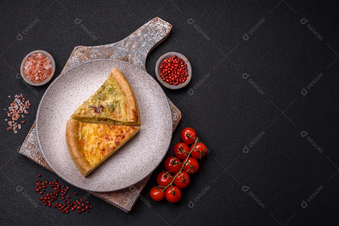 Deliciosa quiche com brócolis, frango ou salmão e queijo com sal e especiarias sobre fundo escuro de concreto