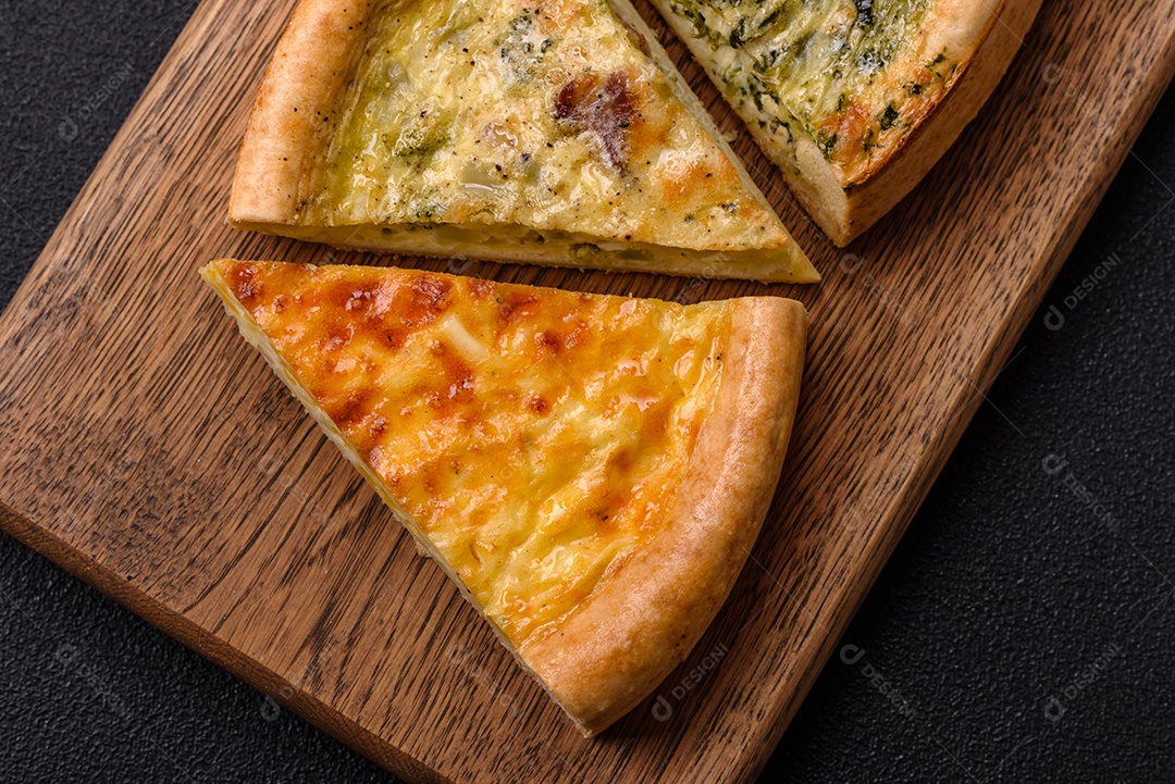 Deliciosa quiche com brócolis, frango ou salmão e queijo com sal e especiarias sobre fundo escuro de concreto