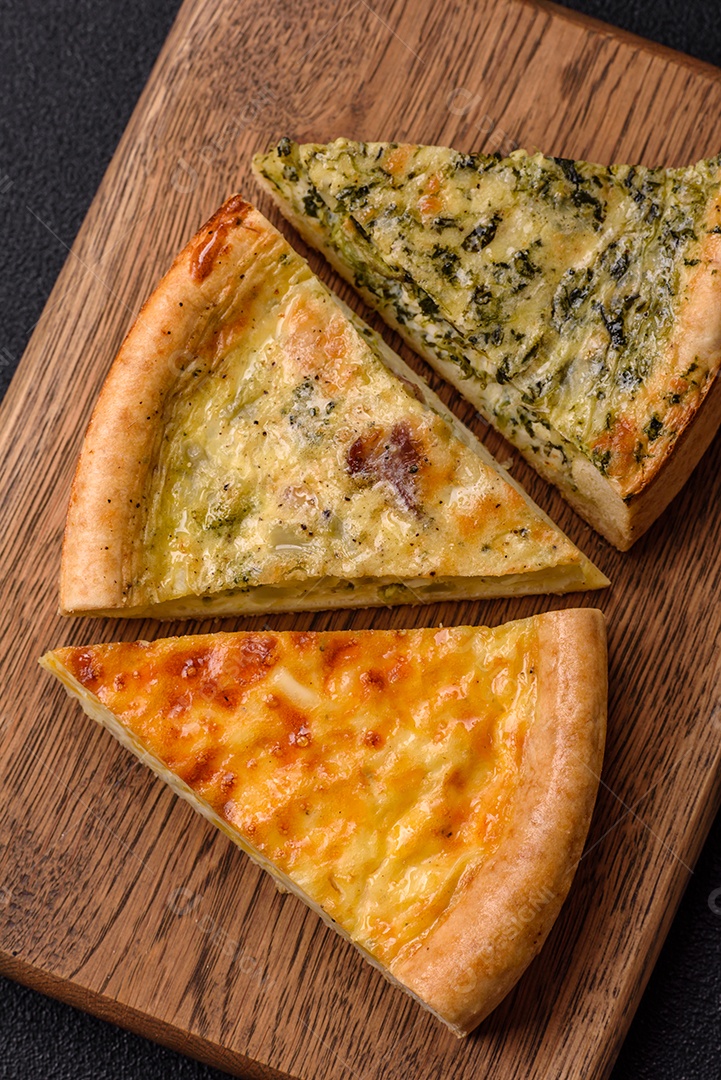 Deliciosa quiche com brócolis, frango ou salmão e queijo com sal e especiarias sobre fundo escuro de concreto