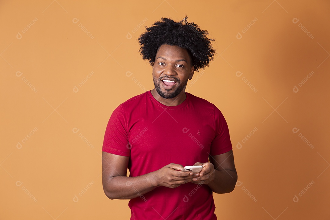 Homem de camiseta vermelha segurando celular e surpreso
