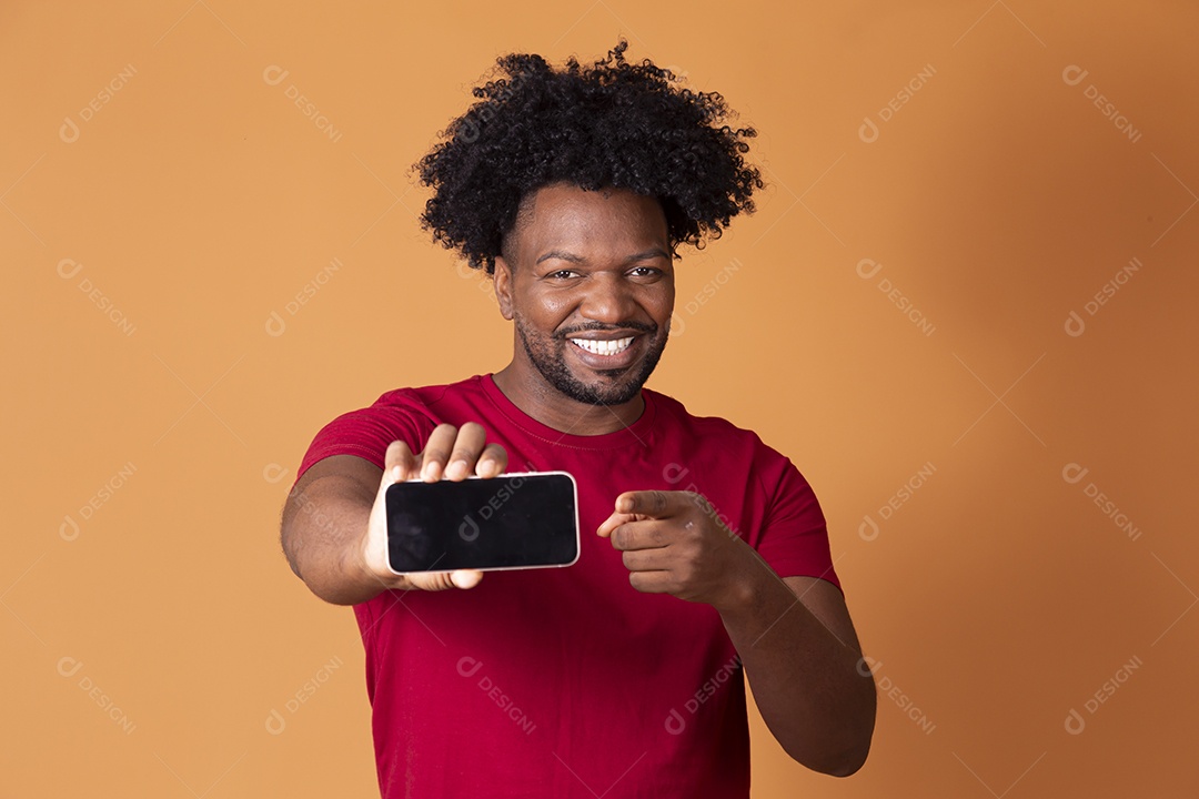 Homem com celular nas mãos sorrindo sobre fundo alaranjado