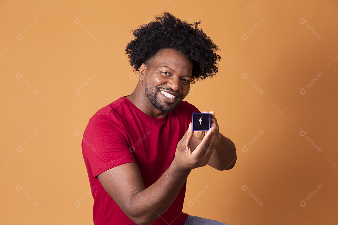 Homem moreno ajoelhado com caixa de aliança