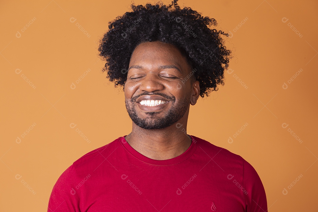 Homem moreno de camiseta vermelha e sorrindo com olhos fechados