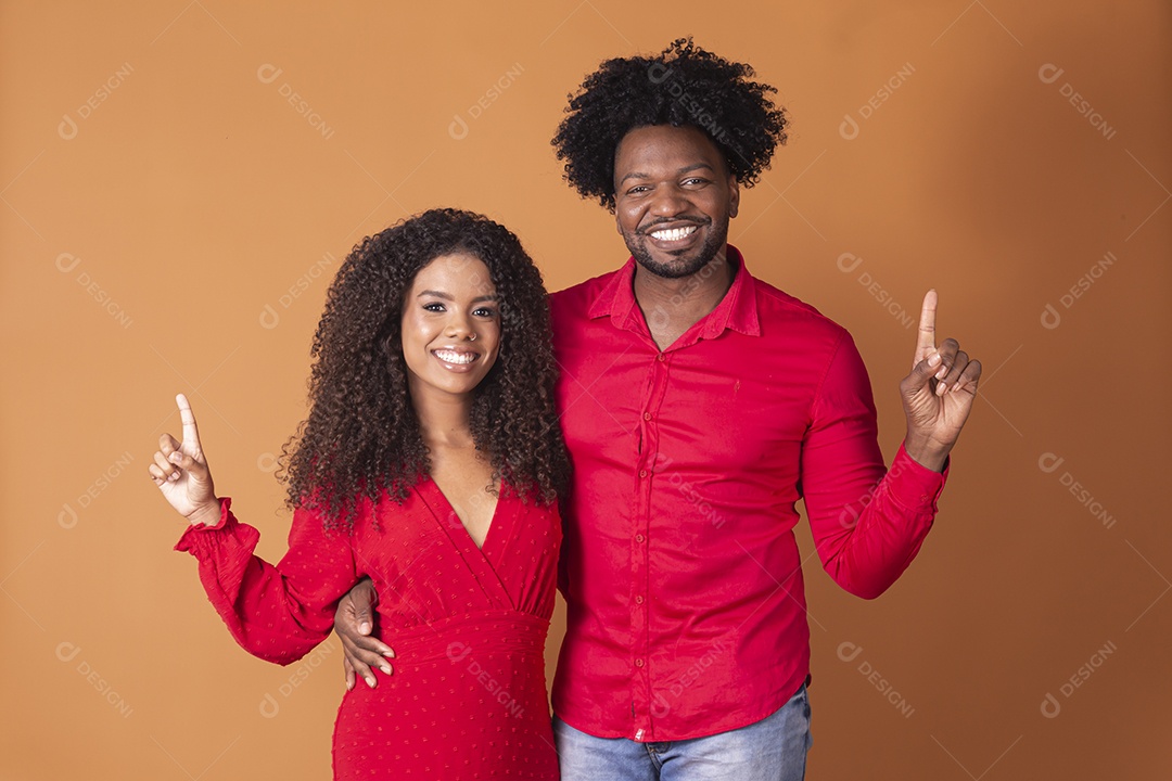 Casal lindo de vermelho apontando para cima