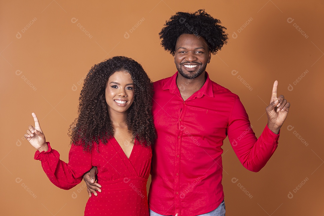 Casal lindo de vermelho apontando para cima