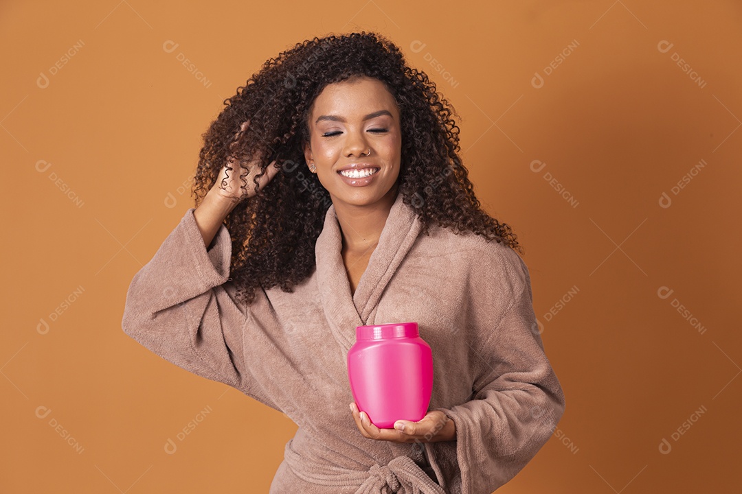 Mulher de cabelos cacheados com pote de creme nas mão
