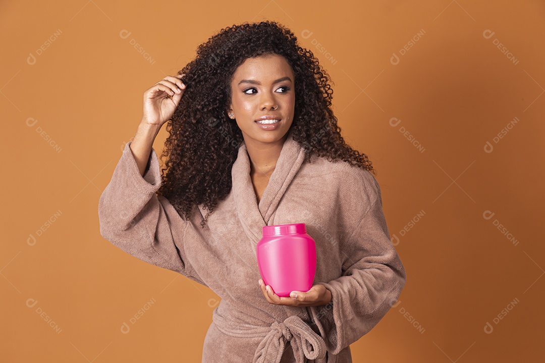 Uma linda jovem de cabelos cacheado com pote de creme nas mãos