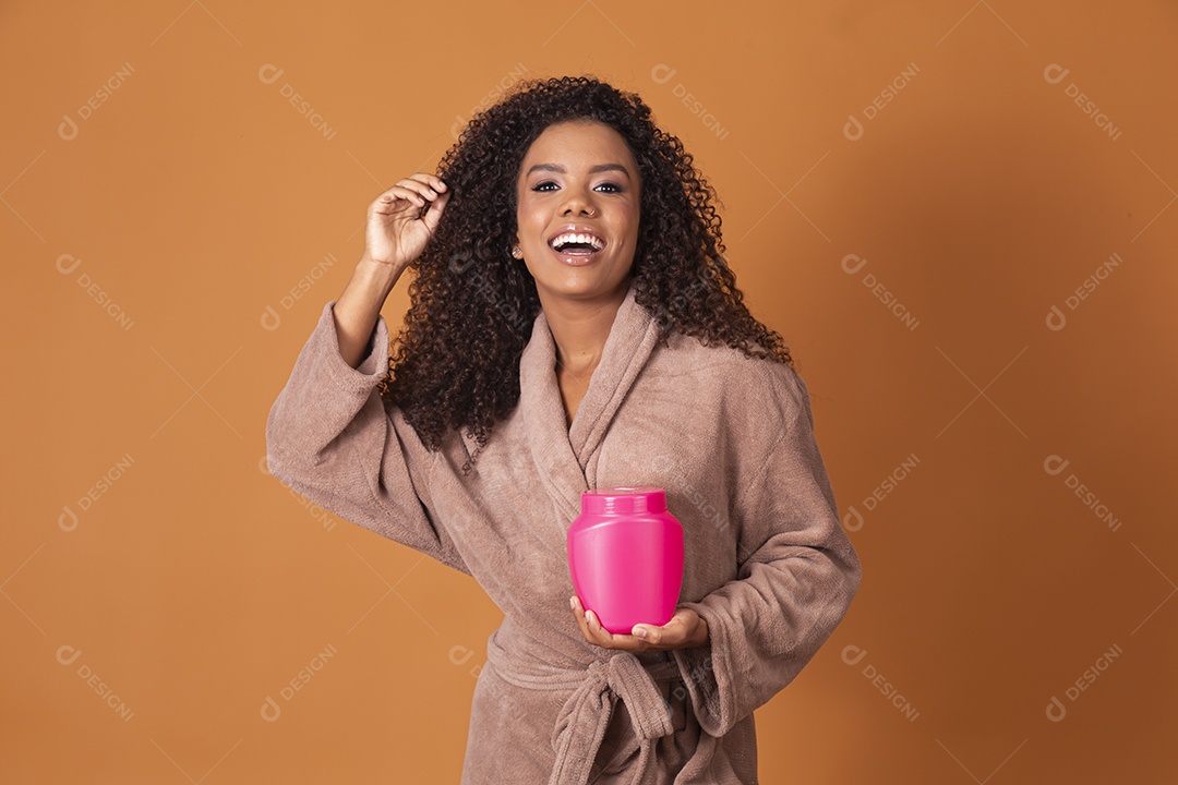 Uma jovem linda cacheada com pote de creme nas mãos