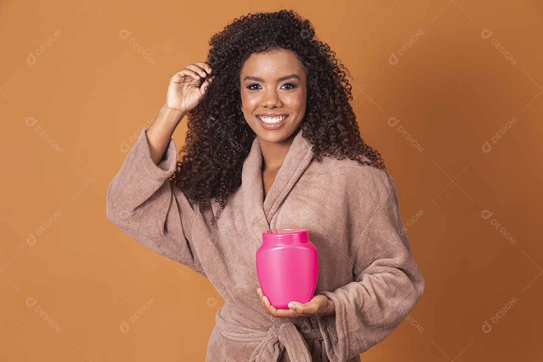 Mulher sorrindo com pote de creme sobre fundo marrom claro