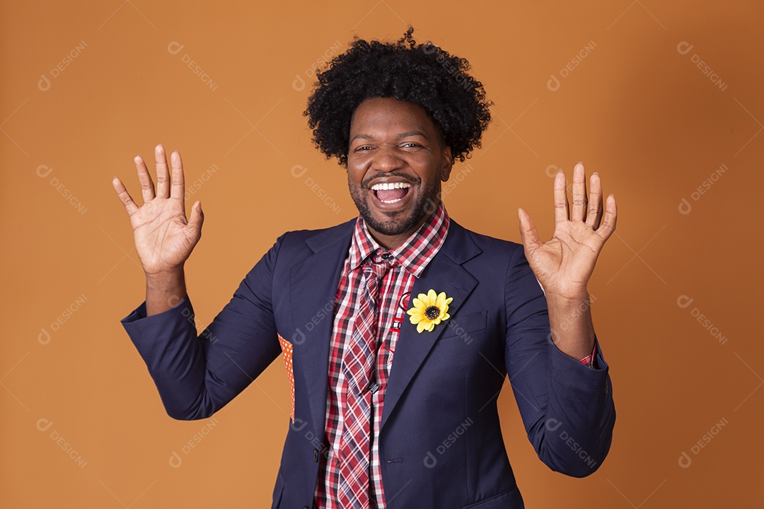 Homem sorrindo trajado para festa junina com mãos pra cima