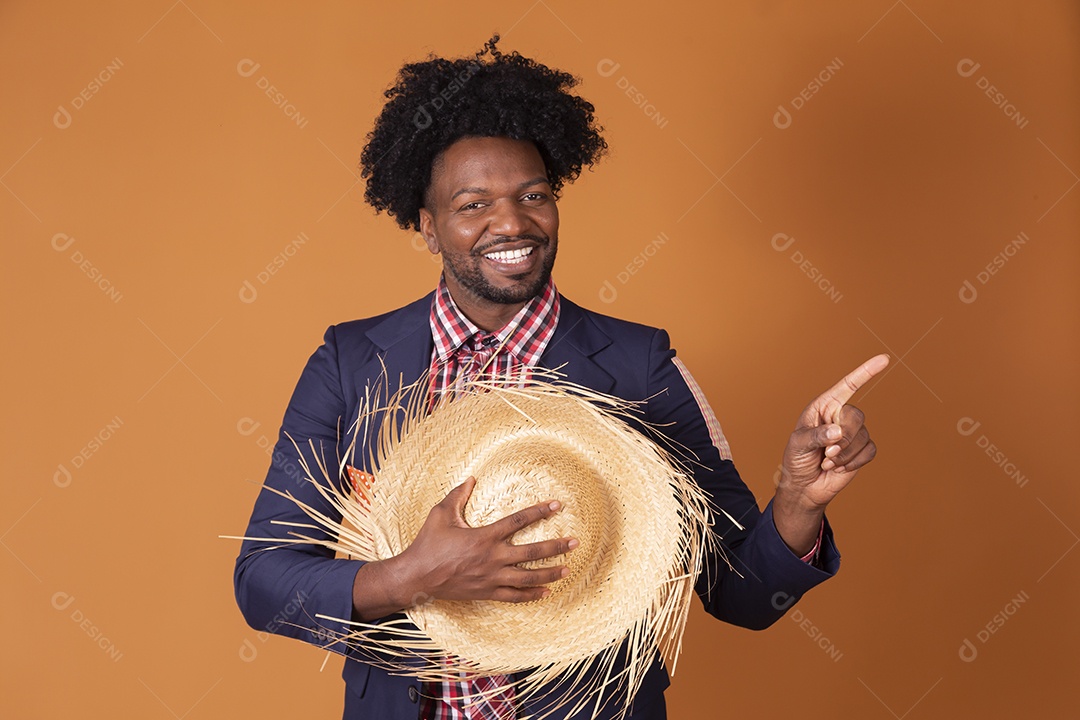 Homem trajado para festa junina com chapéu nas mãos e apontando