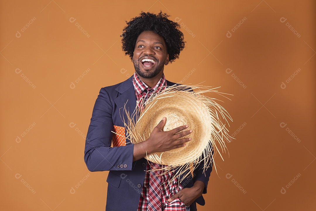 Homem sorrindo trajado para festa junina com chapéu na mão