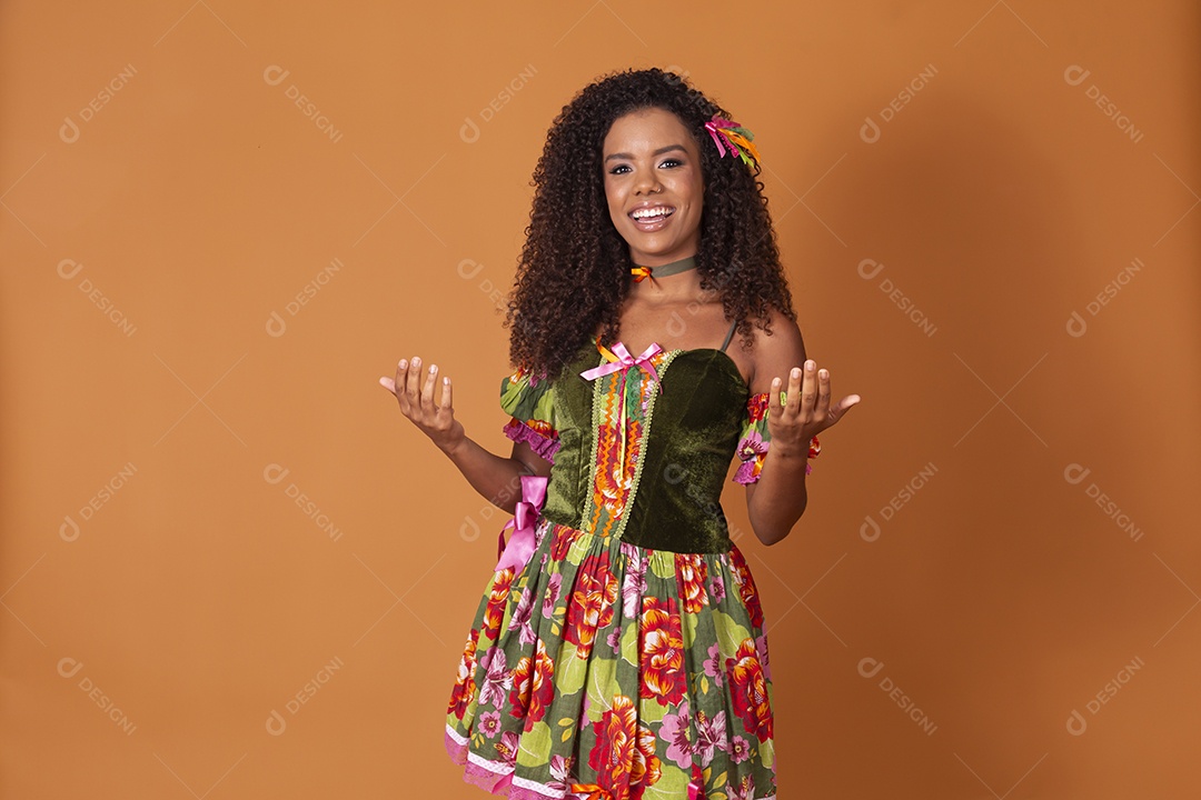 Jovem sorrindo gesticulando sobre fundo marrom claro