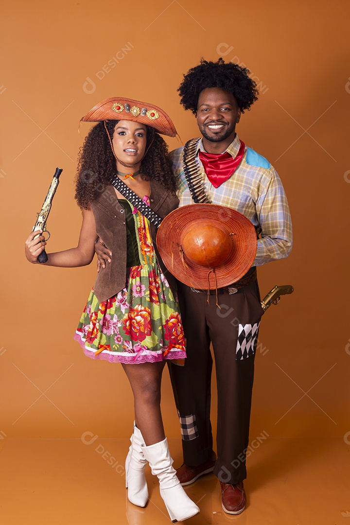 Casal trajados de cangaceiros com arma na mão a caráter para festa junina