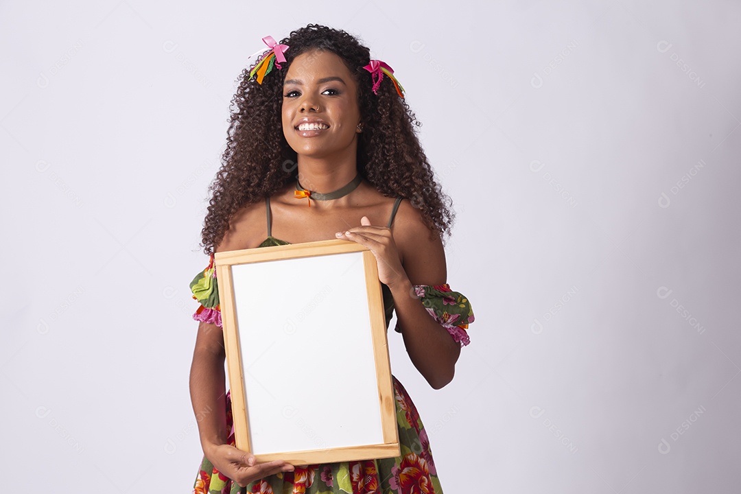 Jovem linda cacheada com quadro na mão e com trajes juninos