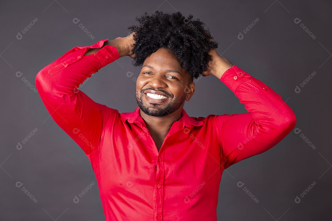 Homem moreno de camiseta vermelha segurando seus cabelos