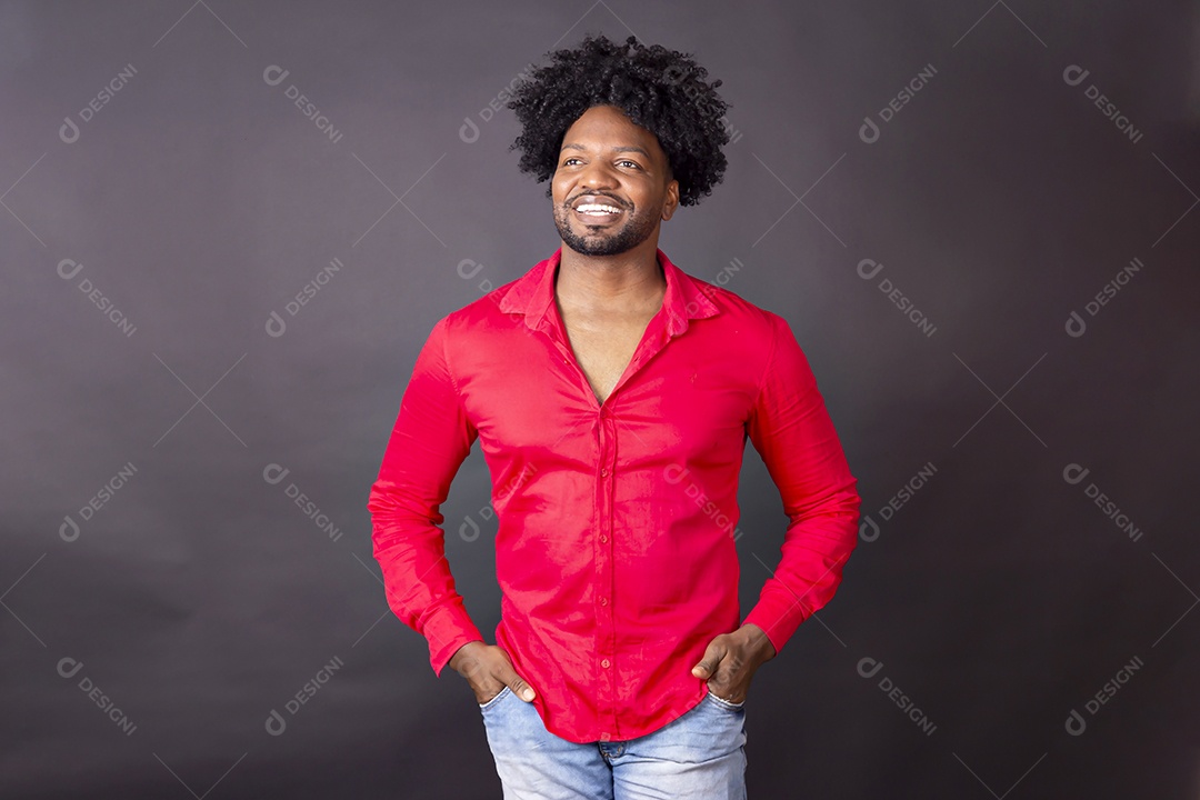 Homem de camiseta vermelha sorrindo de mãos no bolso