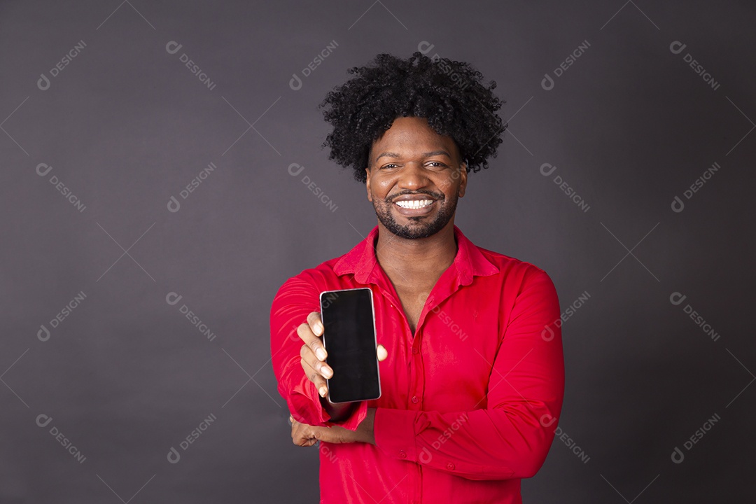Homem moreno com sorriso no rosto e celular na mão