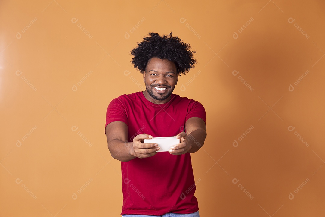 Homem moreno sorrindo segurando celular na mão