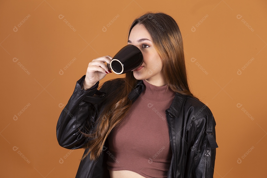 Jovem linda de cabelos claros com jaqueta preta tomando algo em xícara