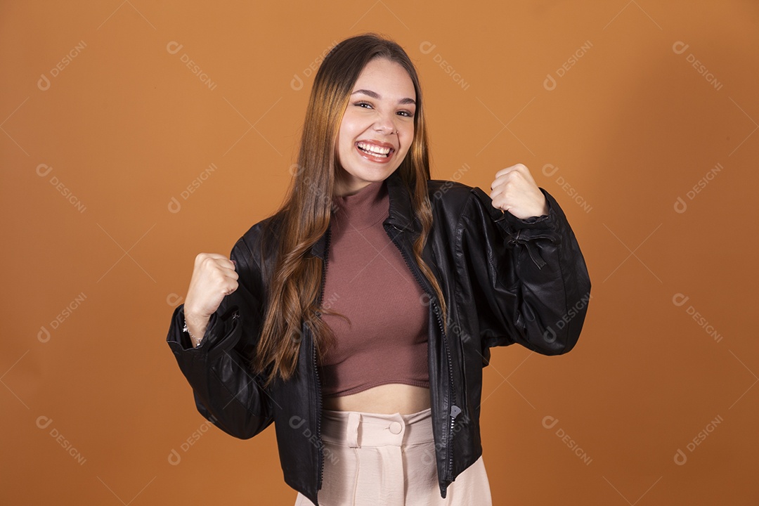 Uma jovem garota sorrindo demonstrando força com jaqueta preta