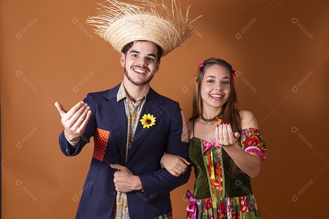 Casal feliz trajados para quadrilha junina fazendo sinal de chamar