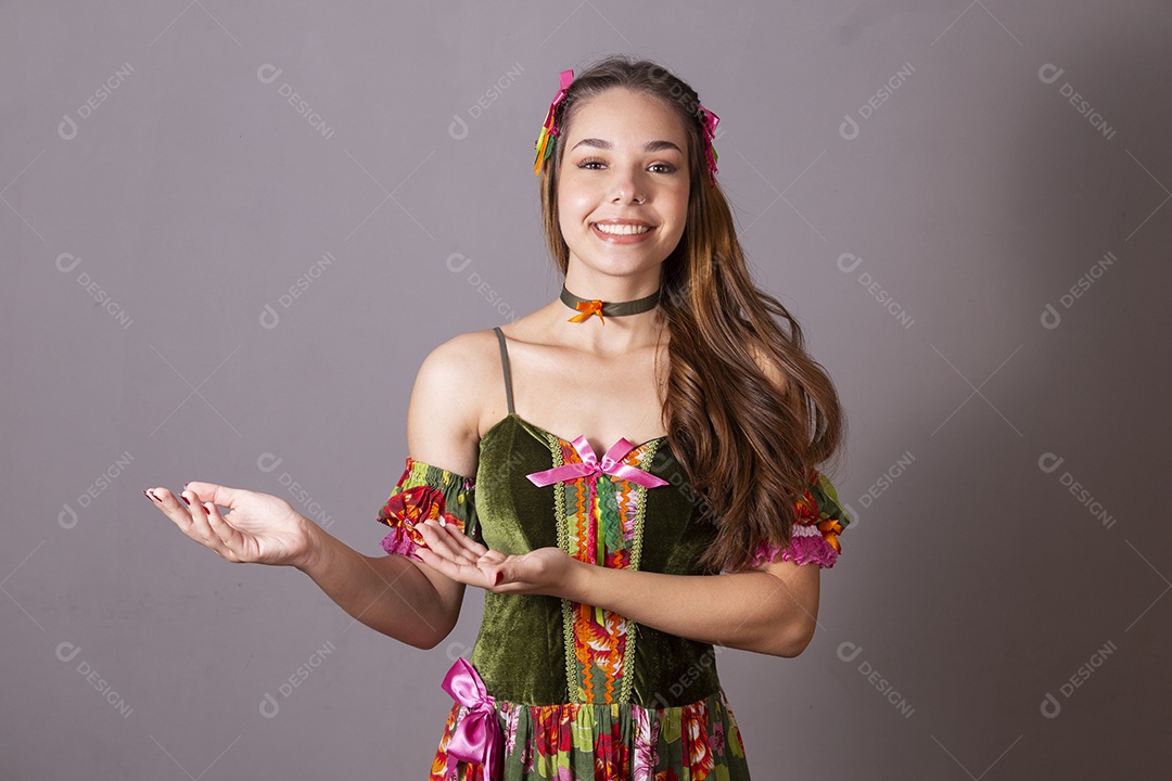 Uma linda jovem vestida de trajes junino com mãos para o lado