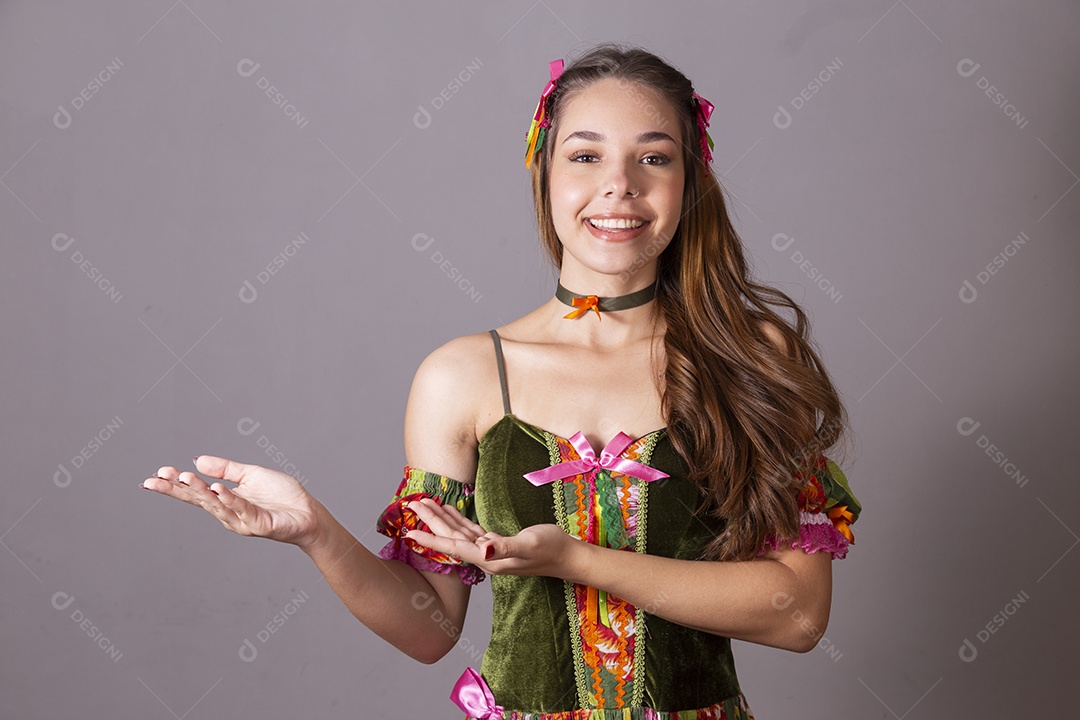 Uma linda jovem vestida de trajes junino apontando para lado