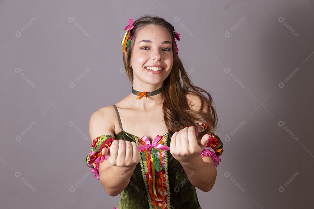 Uma linda jovem vestida de trajes junino com gesto de chamar