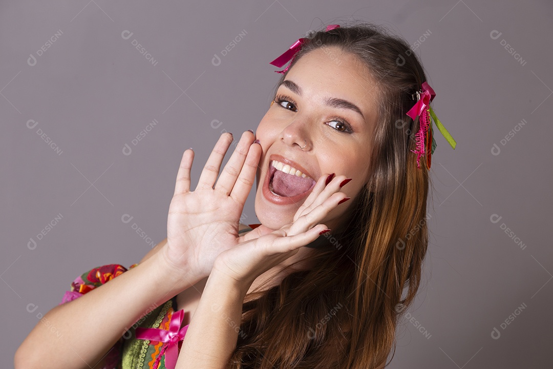 Uma linda jovem vestida de trajes junino com mão na boca