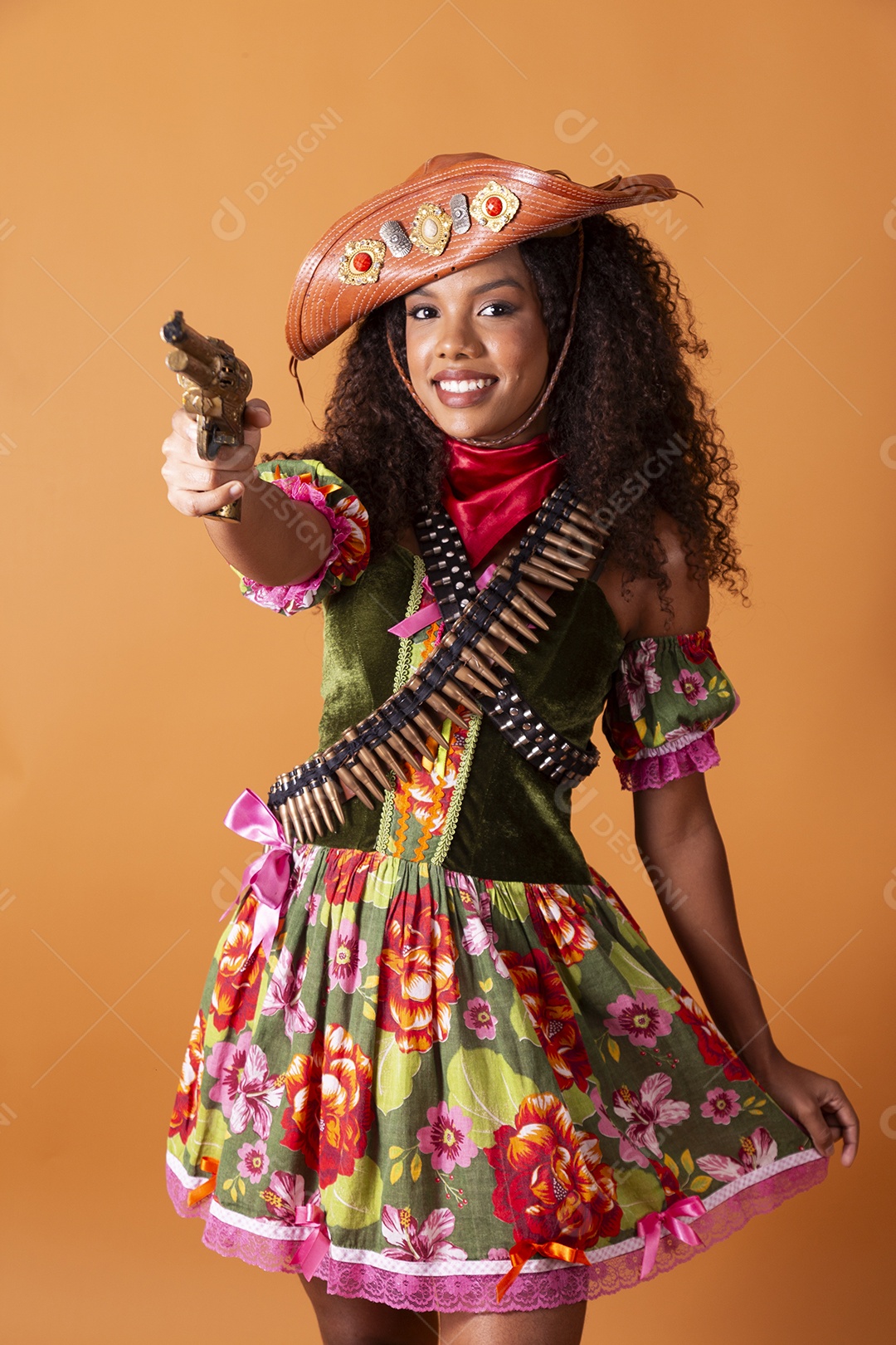 Jovem linda sorrindo cacheada vestida de cangaceira para festa junina apontando arma