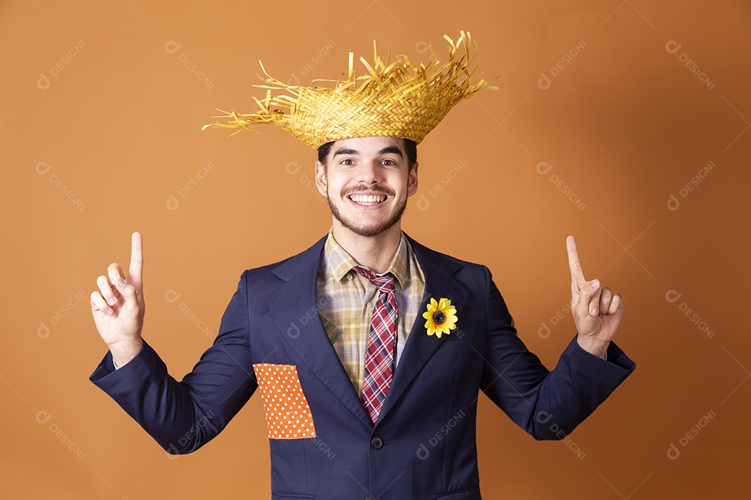 Jovem rapaz vestido a caráter para festa junina com mãos apontando para cima